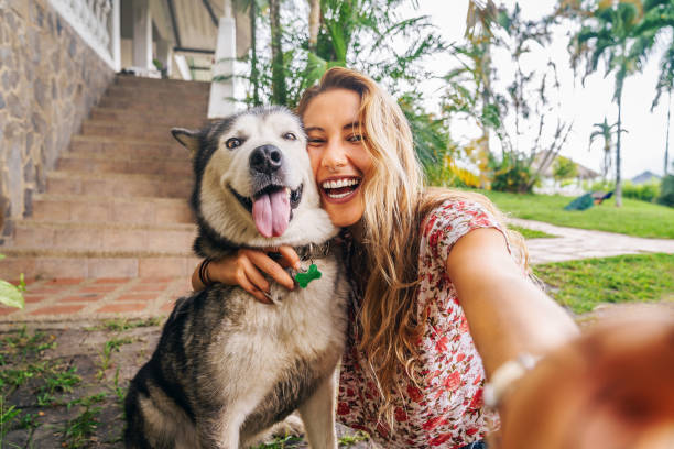 Woman taking a selfie with a husky dog outdoors
